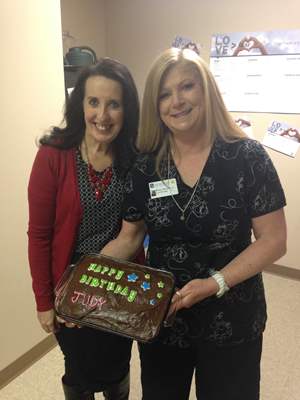 two woman holding up a homemade birthday cake